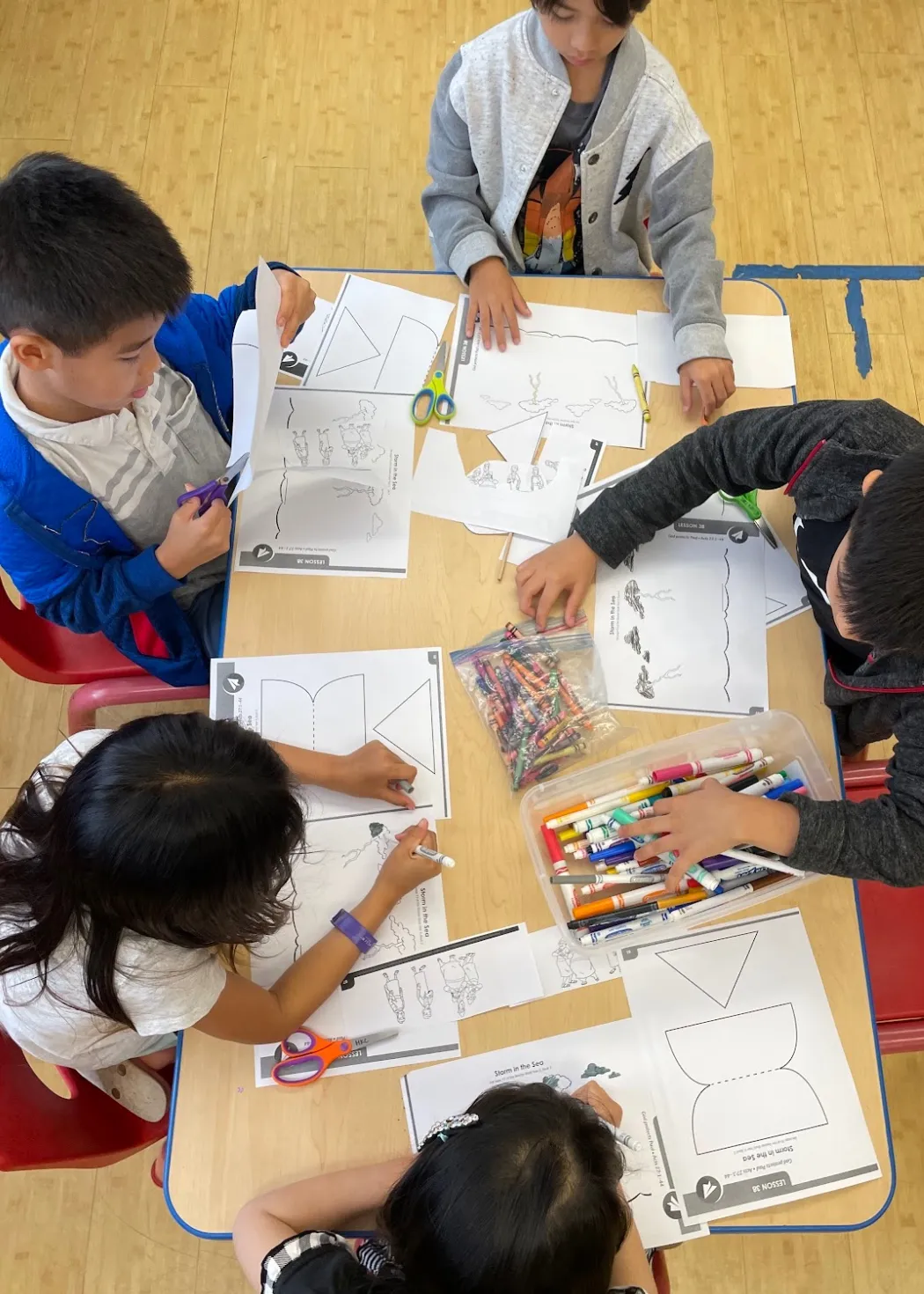 Children working on a Bible lesson craft around a classroom table