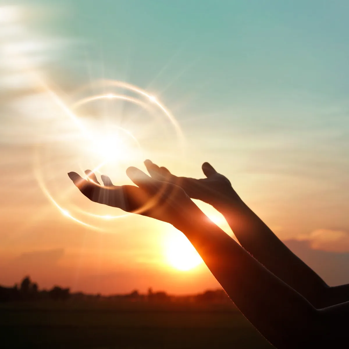 Open hands lifted toward the sunset sky in prayer