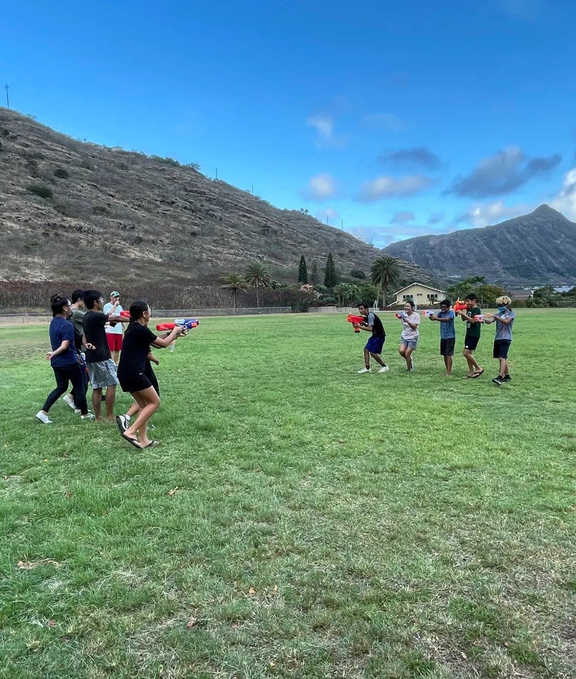 Students playing a water game on a grassy field below the Koko Head ridge